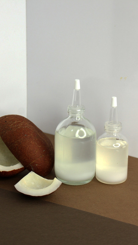 شیشه روغن نارگیل ارگانیک در کنار تکههای نارگیل طبیعی